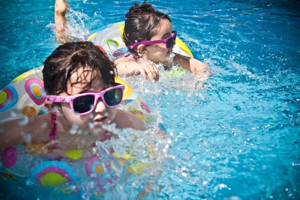 Children playing in a shallow paddling pool in a garden