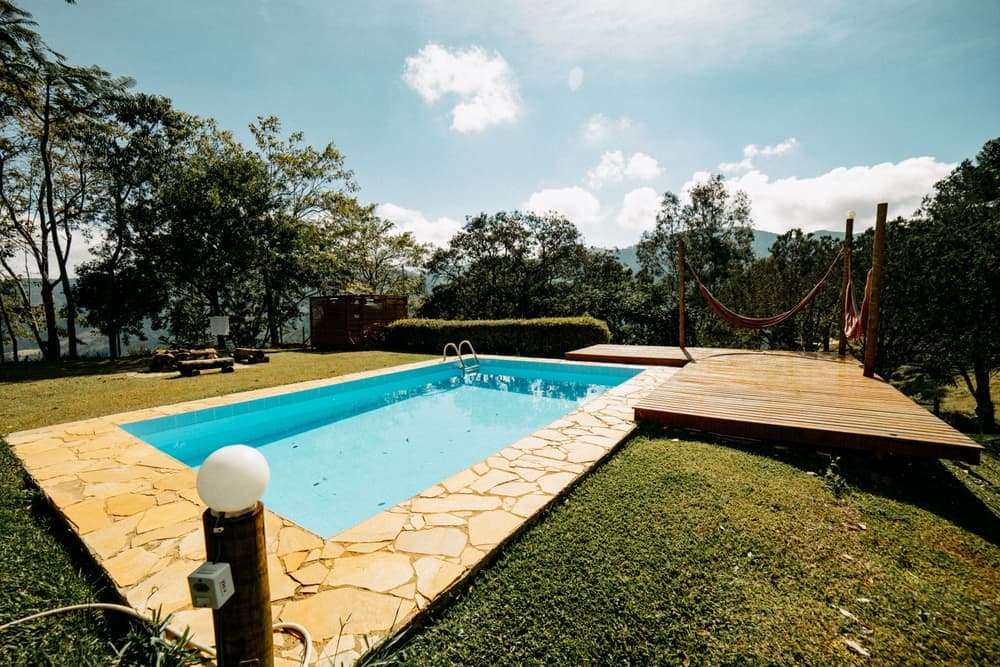 An above-ground pool with clear water set in a green backyard