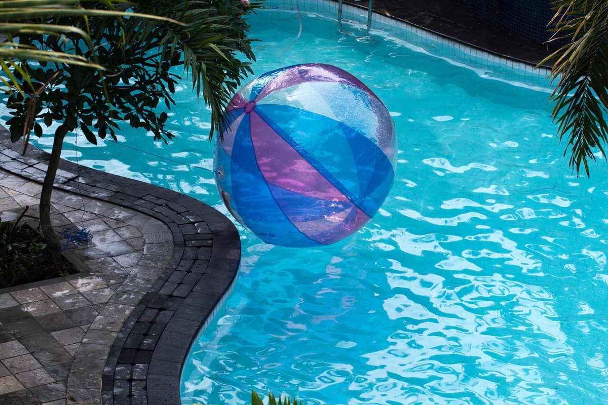 A beach ball floating on the surface of a backyard pool