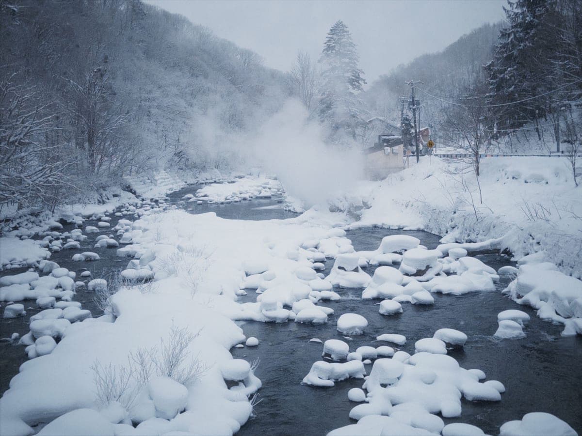 Steam rising from a river among snow-covered rocks in winter