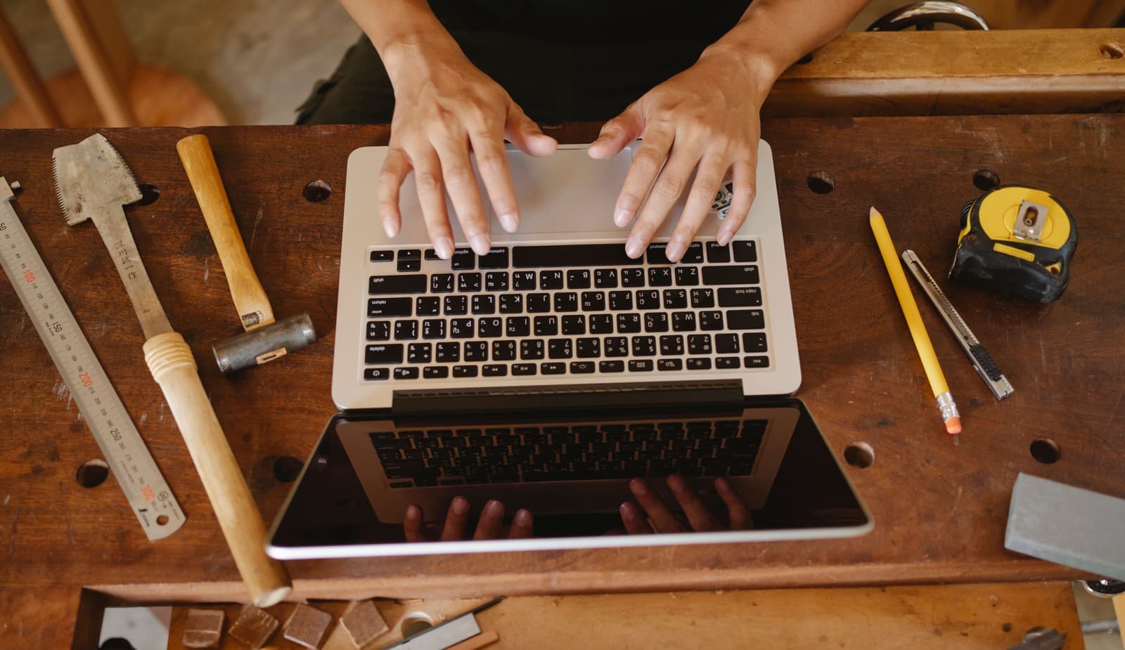 Hand tools arranged around a laptop on a workbench