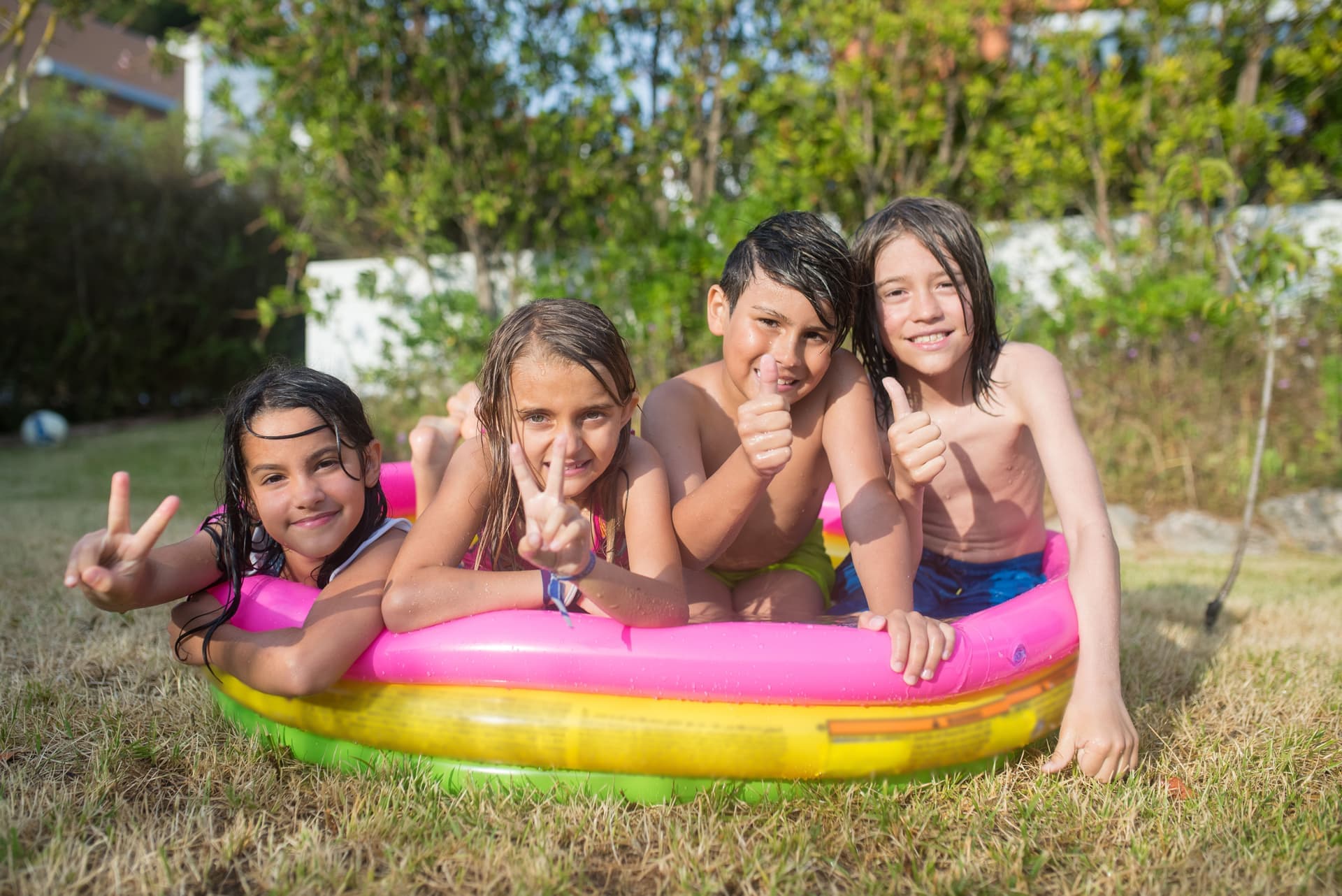 Children playing in an inflatable pool in a garden