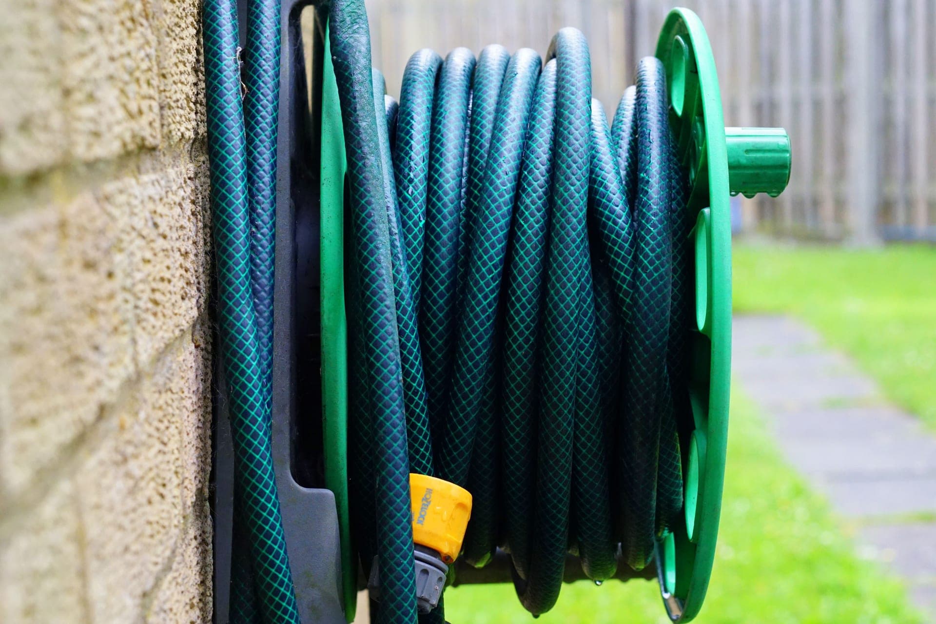 A coiled garden hose on a wall-mounted reel
