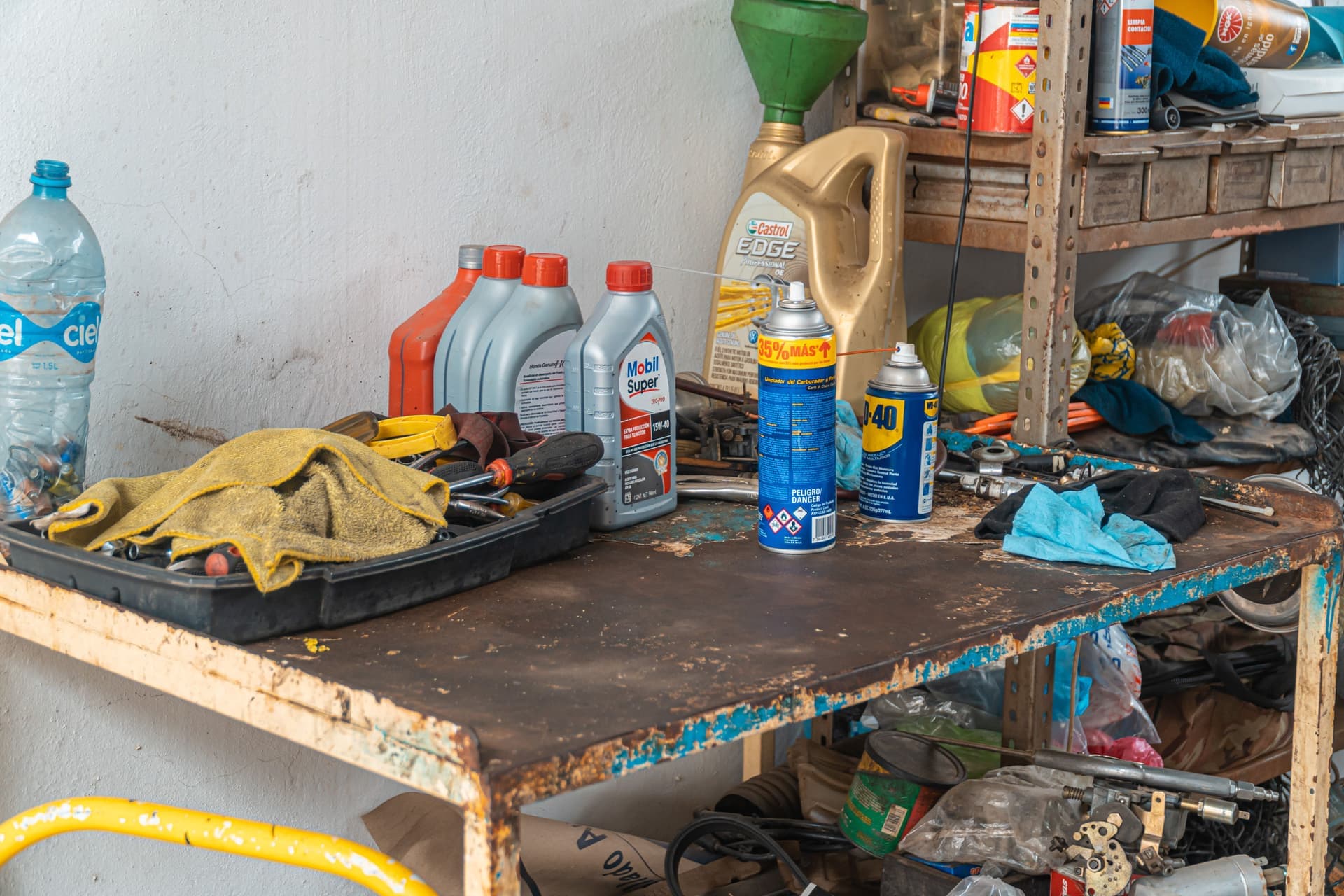 A cluttered garage workbench with tools and containers