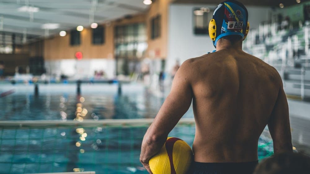 A person skimming the surface of a swimming pool with a net