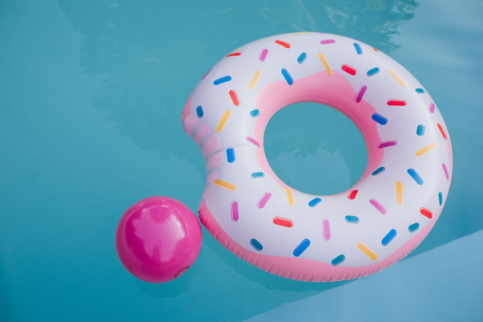 An inflatable ring float and a ball beside a pool