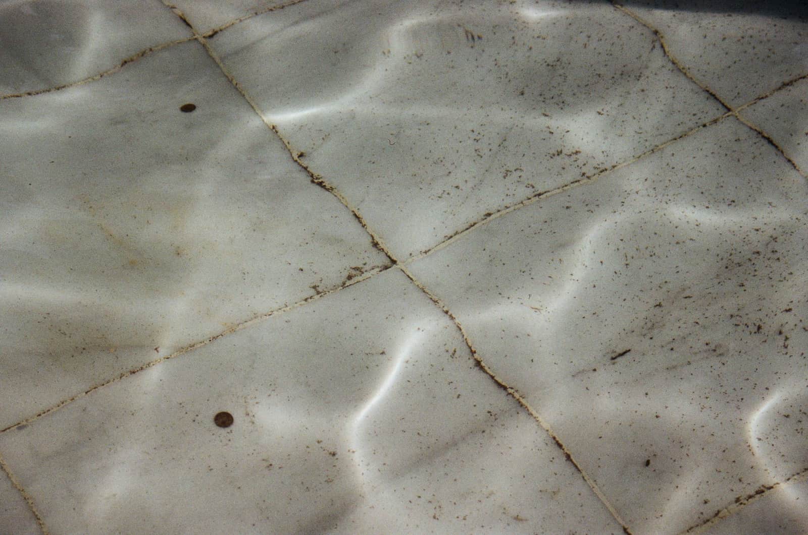 Pale mineral staining across a tiled pool surface seen through water