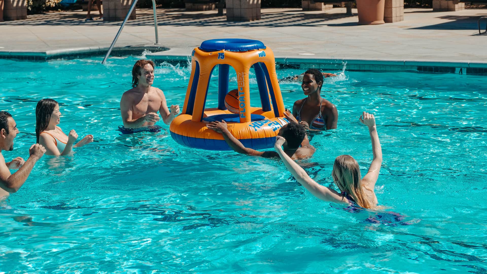 Friends playing with an inflatable basketball hoop in a pool