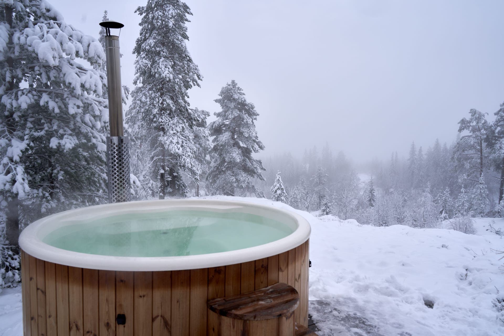 An outdoor hot tub among snow-covered trees in winter
