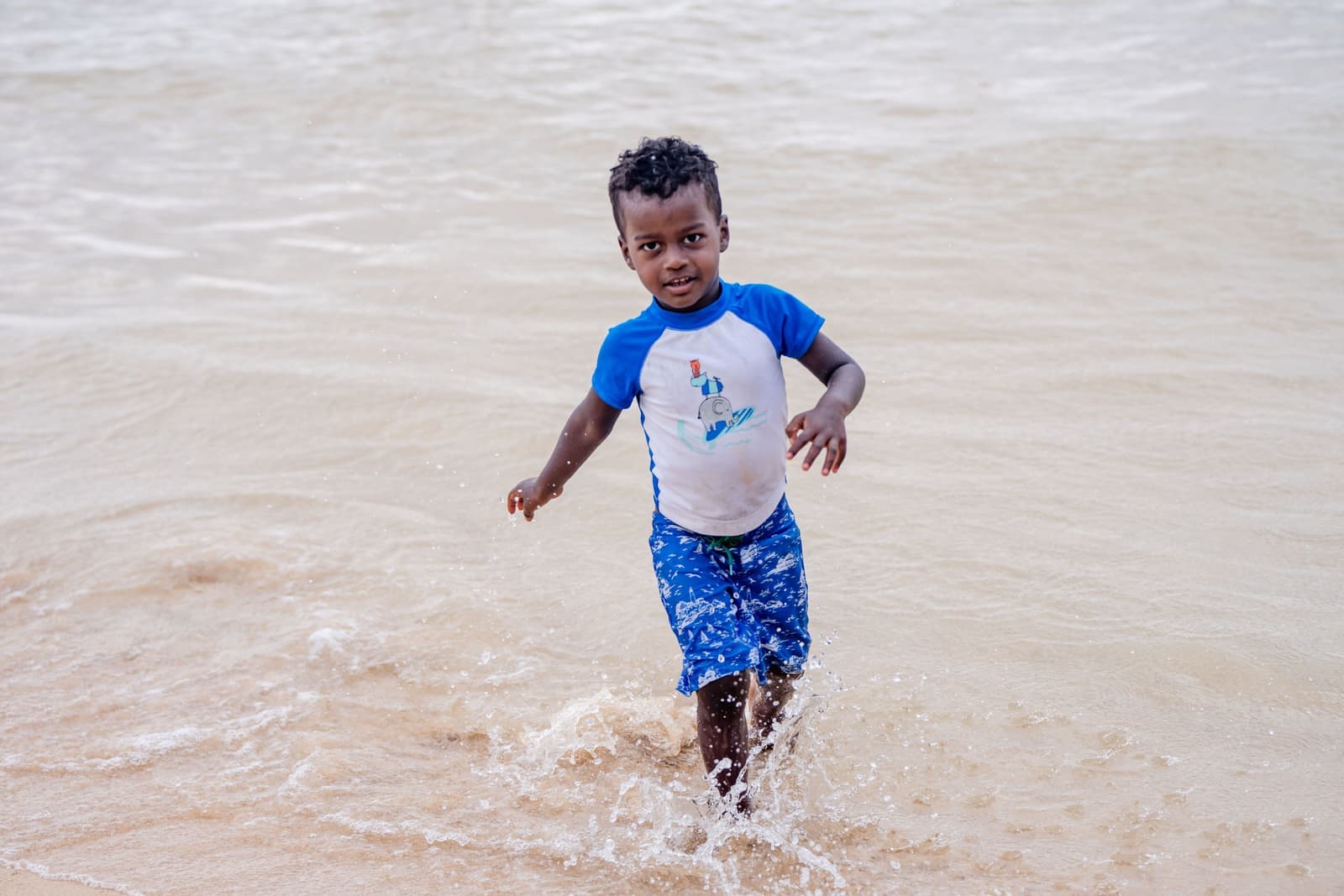 A small child playing in shallow water