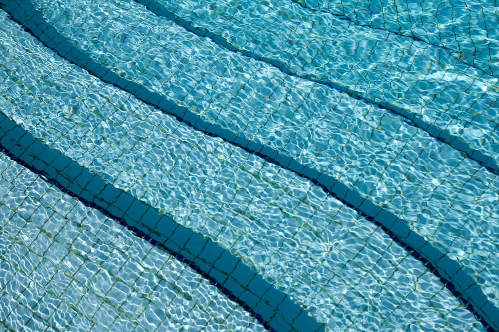 The blue vinyl surface of a pool liner under clear water