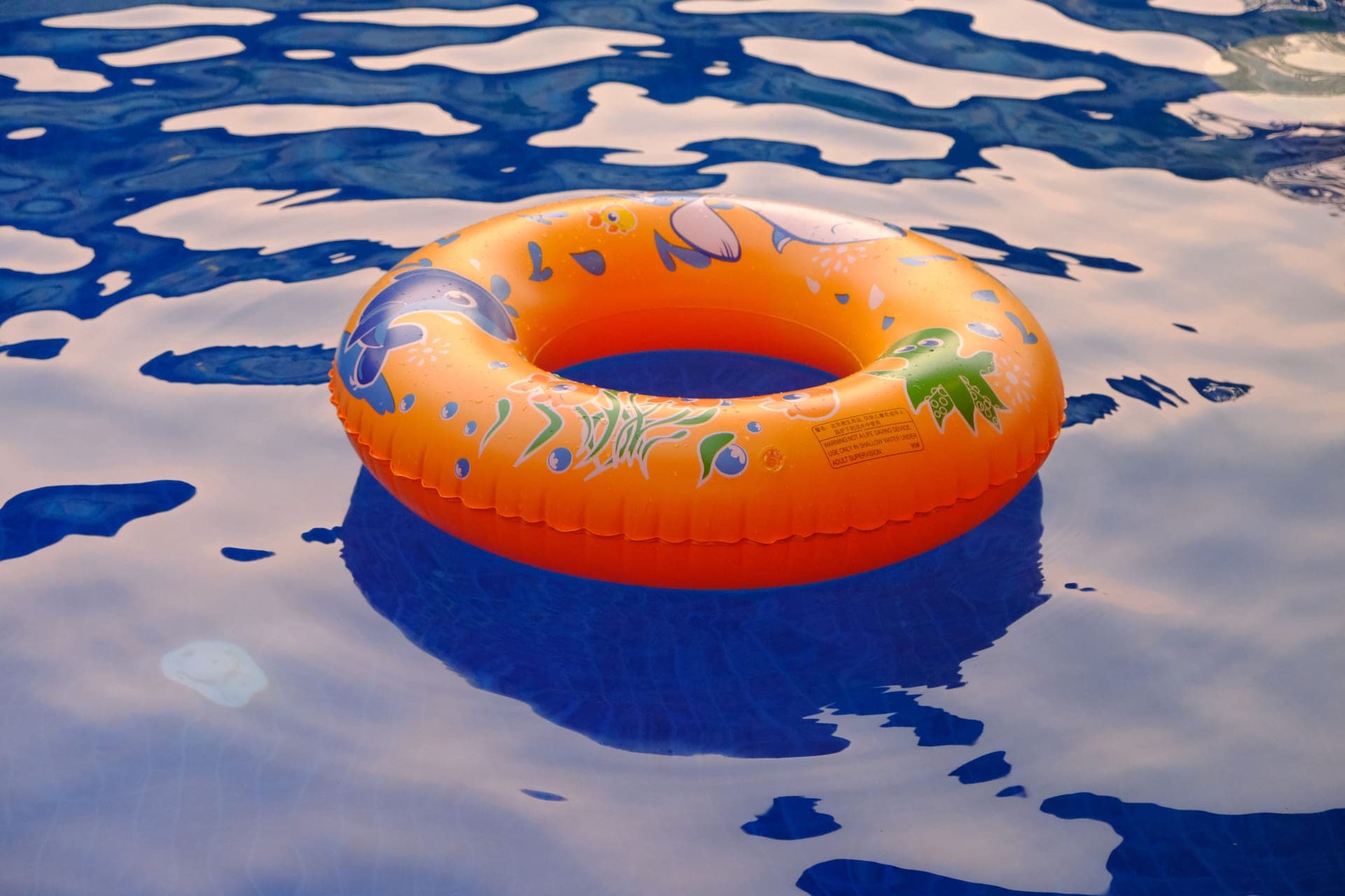 An orange inflatable ring floating on sunlit water