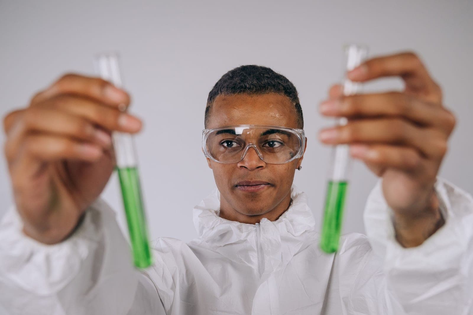 A laboratory technician holding test tubes of colored liquid