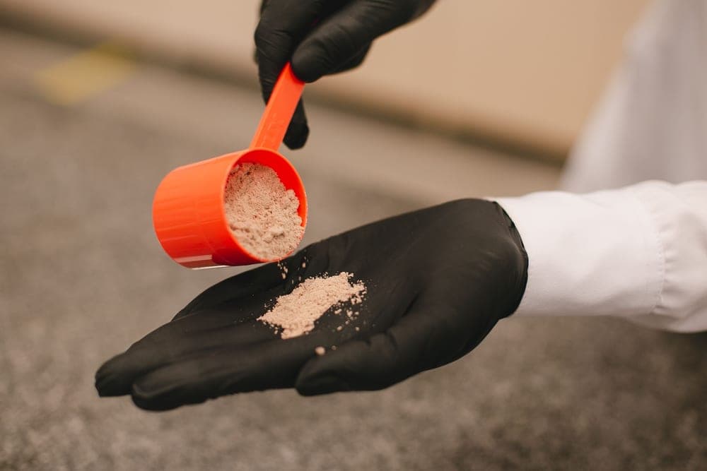 White granular chemical being scooped from a bucket