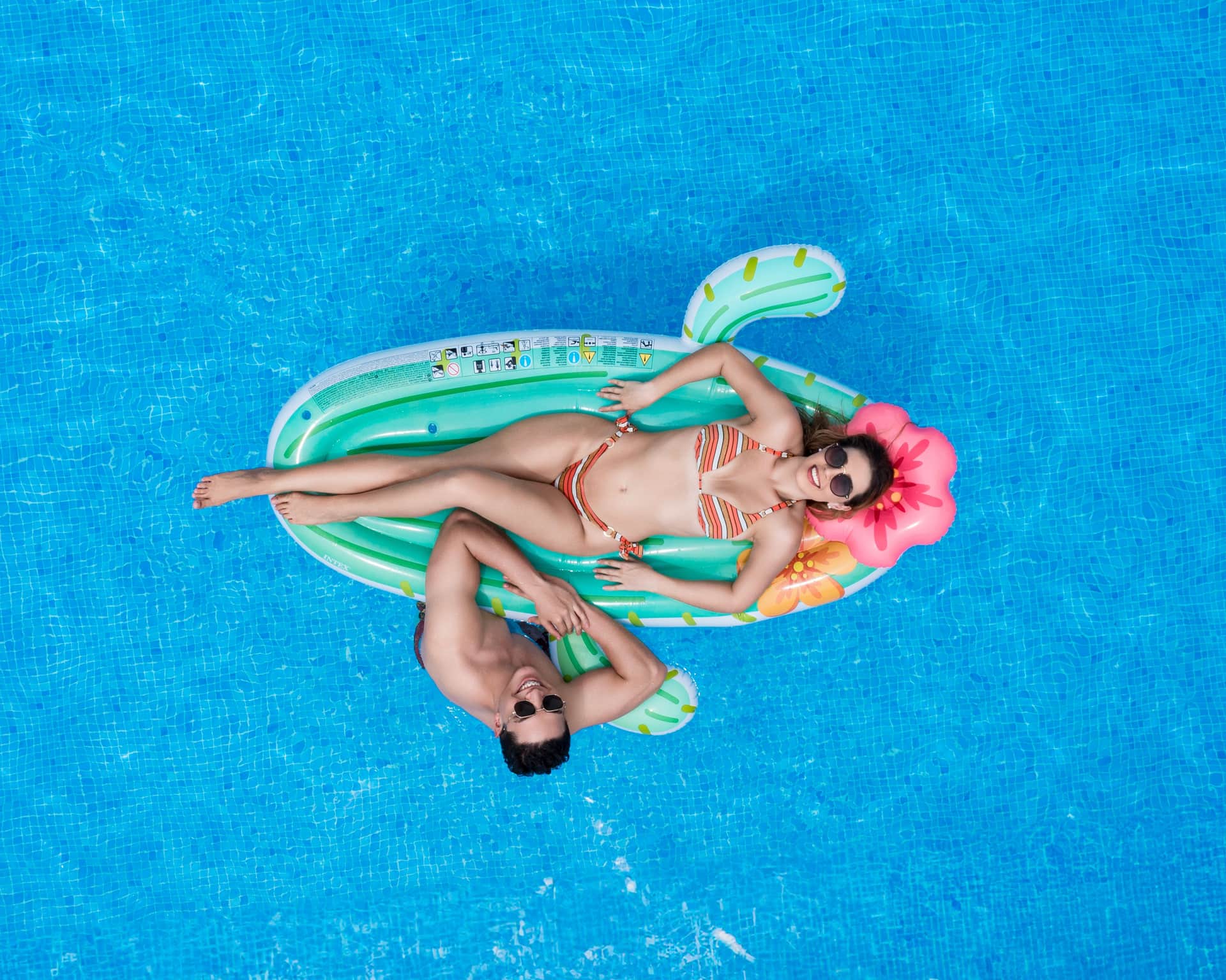 An aerial view of a couple relaxing on a pool float