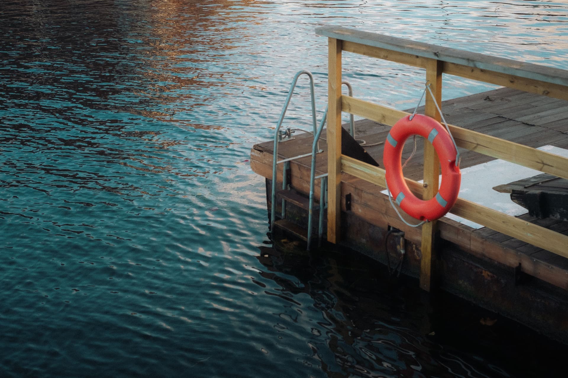 An orange life ring mounted on a dock beside the water