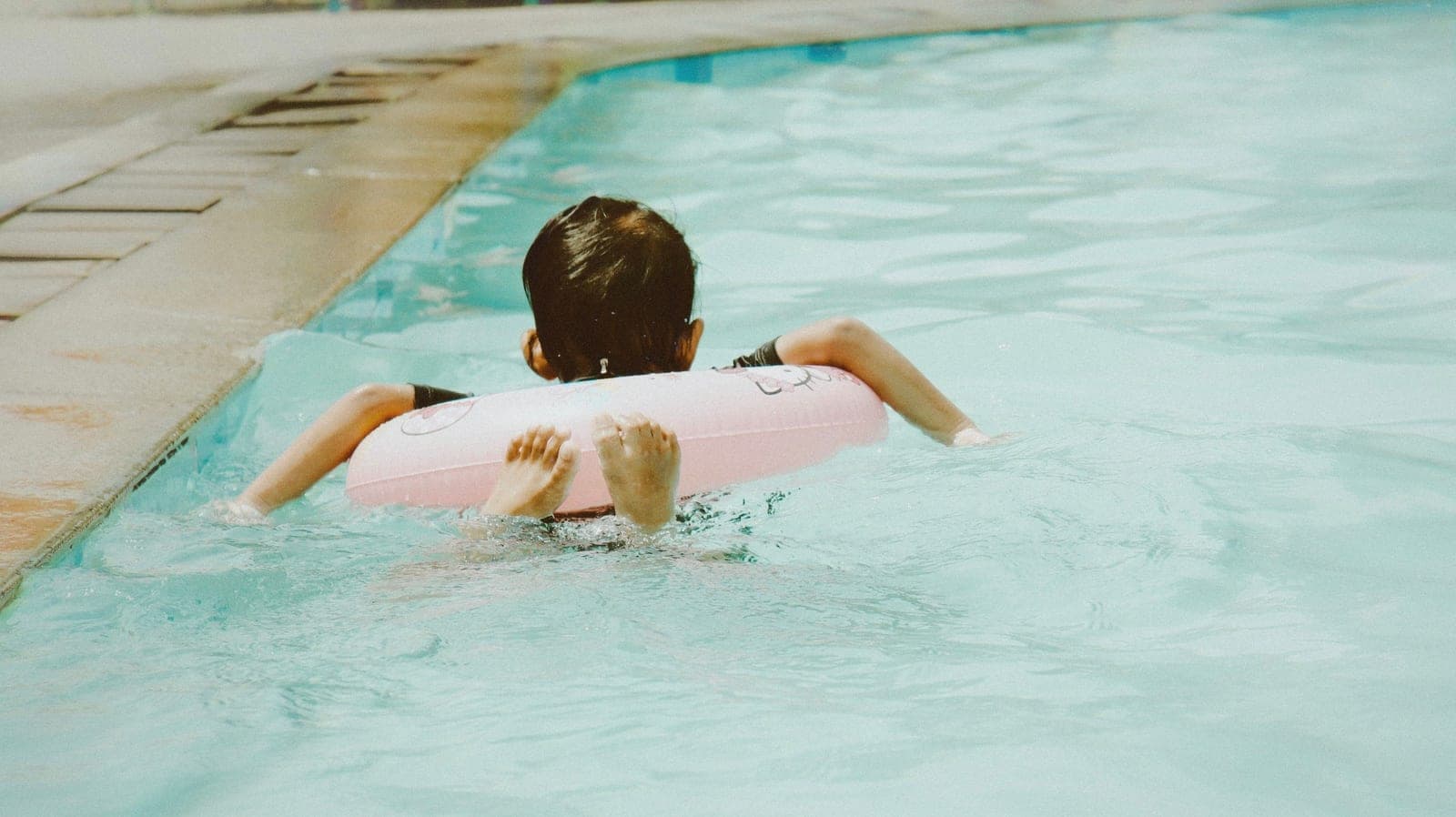 A young child wearing a flotation aid in a swimming pool