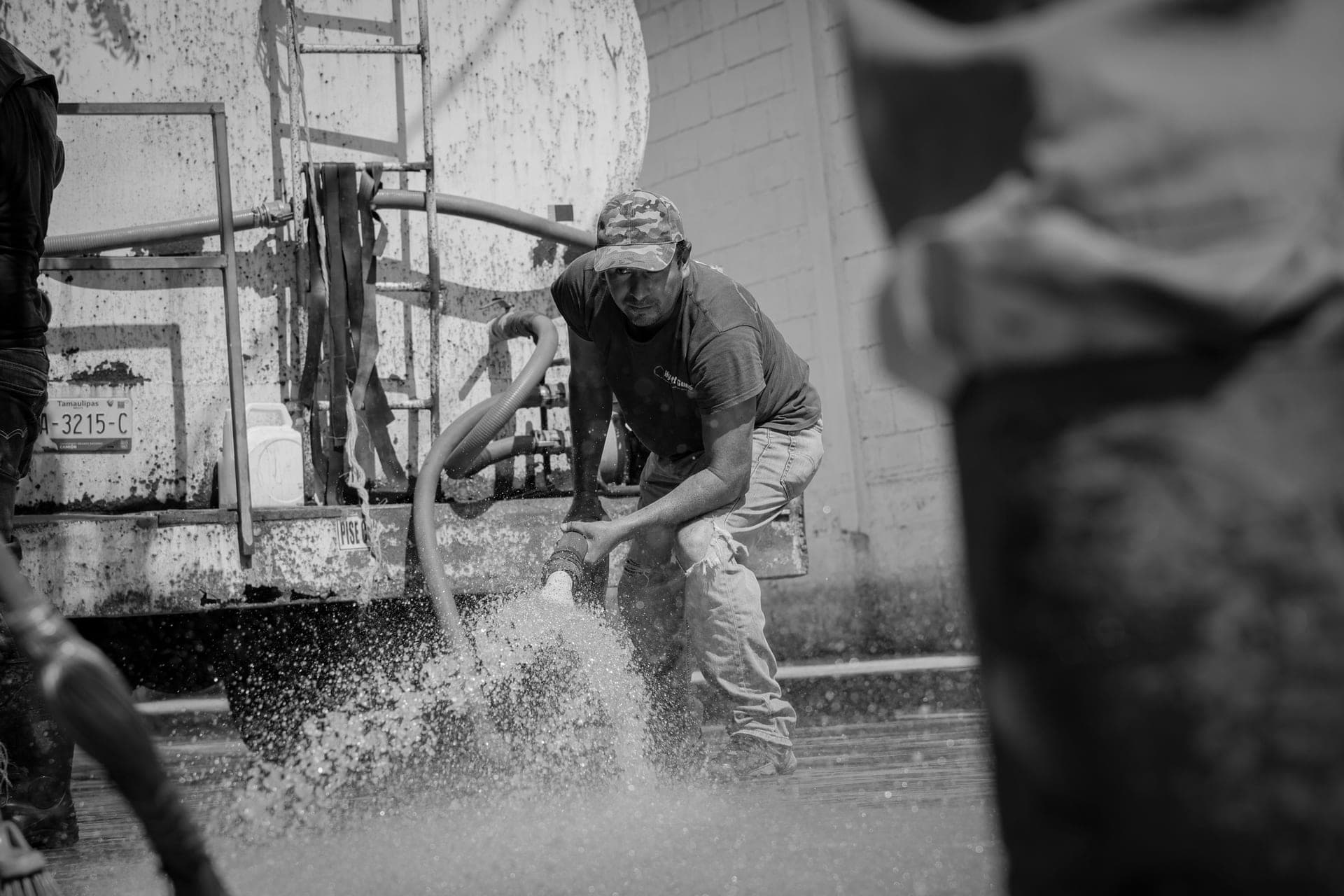 A worker handling a hose beside a large tanker truck