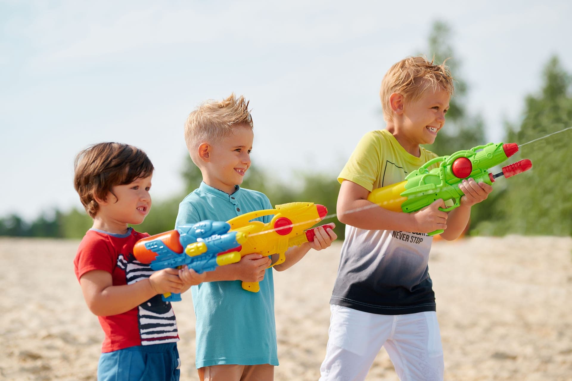 Three children playing with water guns