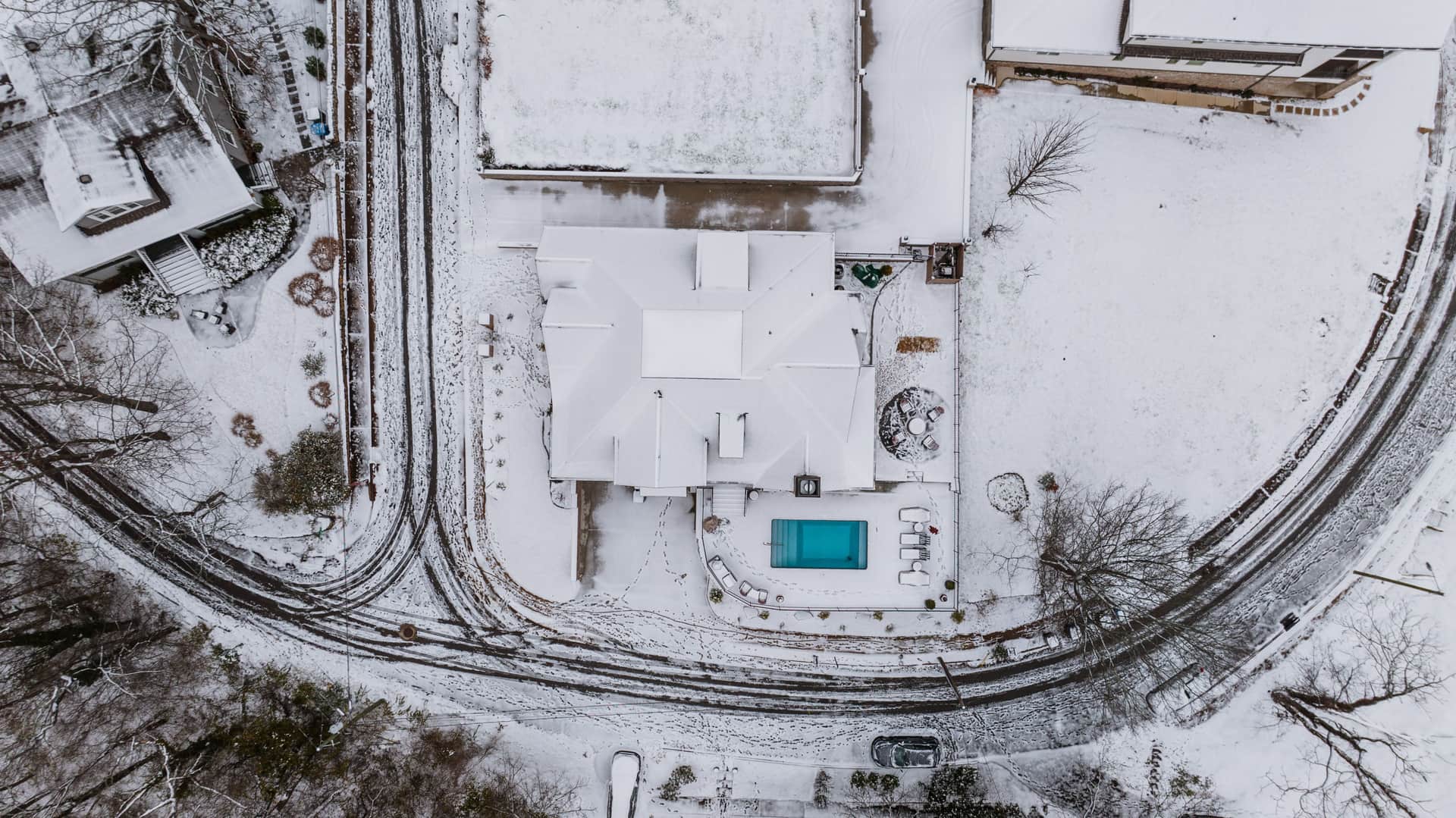 An aerial view of a snow-covered property with a swimming pool