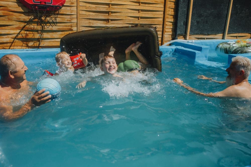 A family playing together in a backyard swimming pool