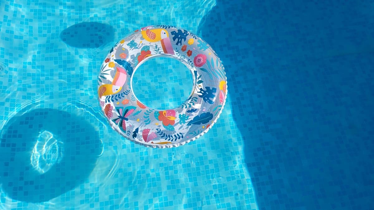 An above-ground pool with clear blue water in a fenced backyard